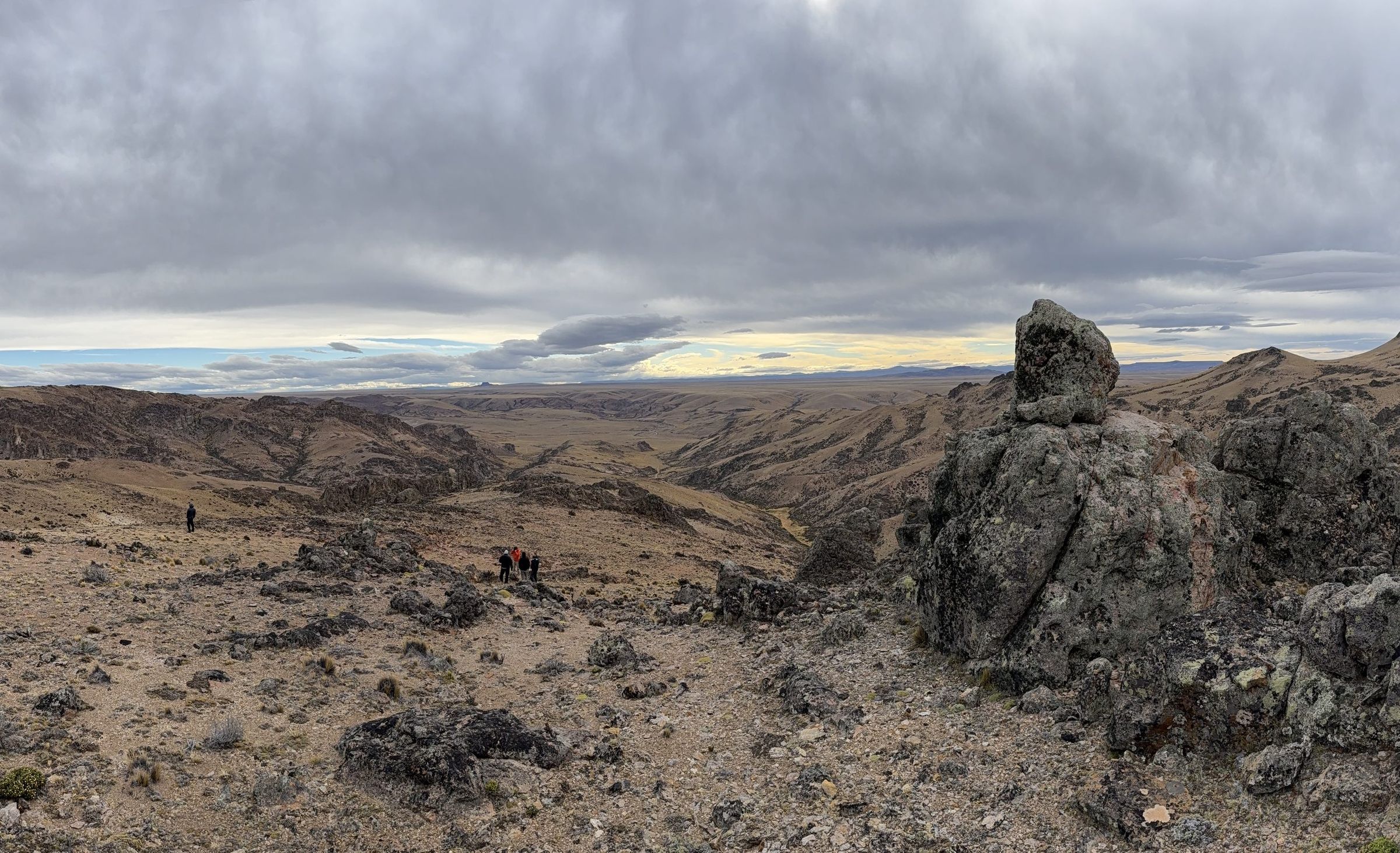 Panoramic view of the Deseado Massif, with the field team crossing a rocky ridge
